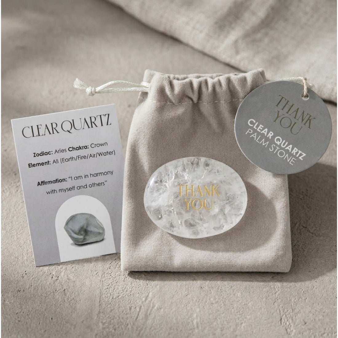 Thank You Clear Quartz Palm Stone with gold Thank You etching, shown close-up with tag and rock, includes soft pouch and affirmation card.