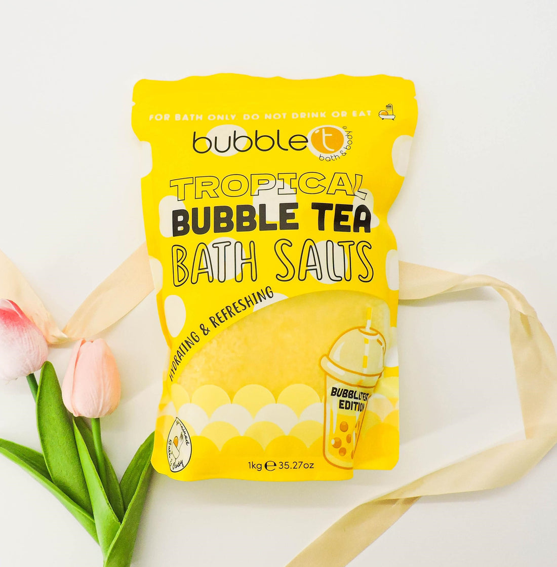 Tropical Bubble Tea Bath Salts package with a pink flower and logo, highlighting its fruity, hydrating benefits for a refreshing self-care experience.