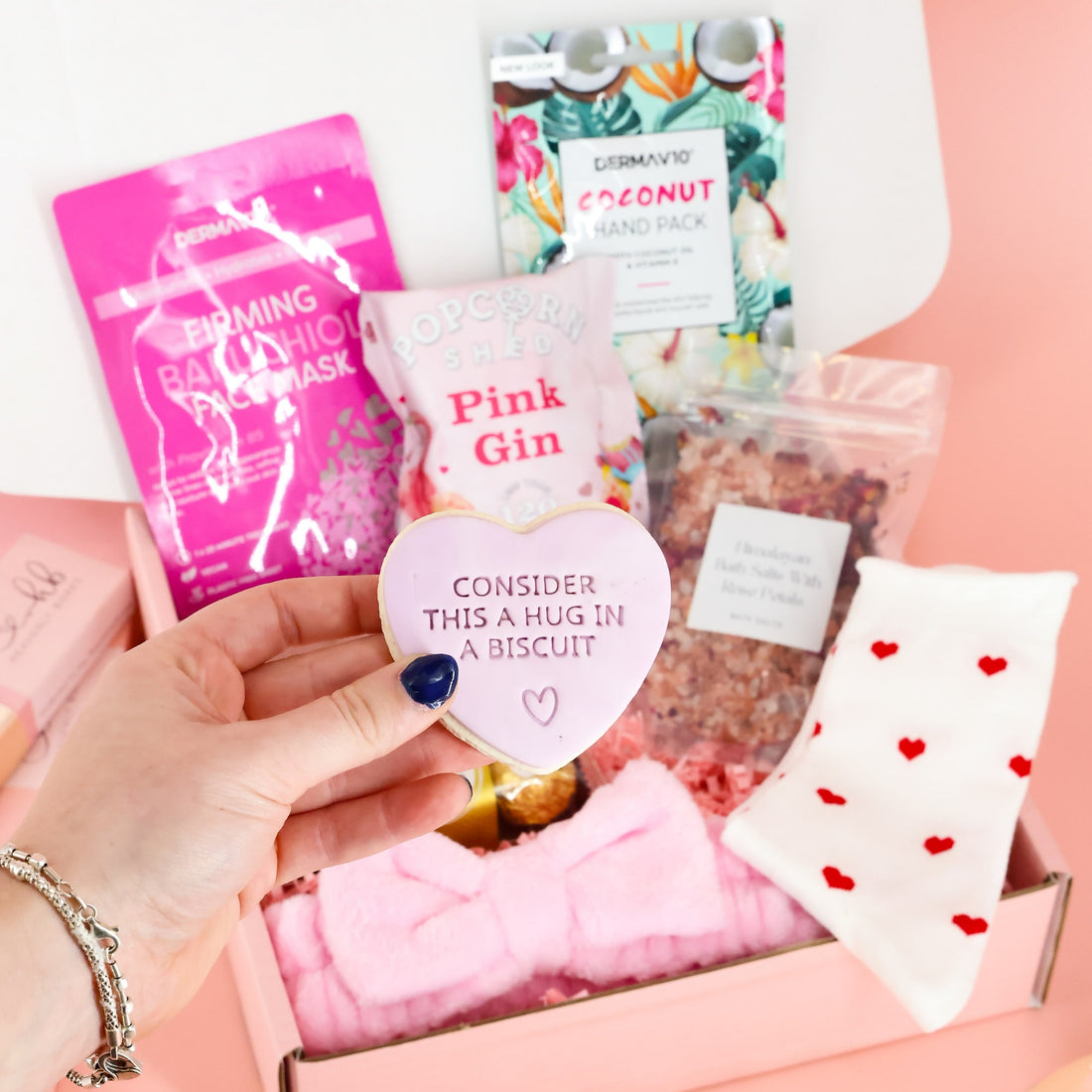 Heart-shaped iced biscuit with "Consider this a hug in a biscuit" message in a self-care package for mental health or birthdays.