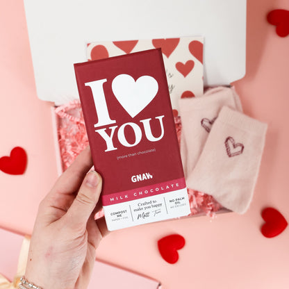 Valentines letterbox gift by Heavenly Boxes styled with heart socks, chocolate bar, biscuit, and love themed card