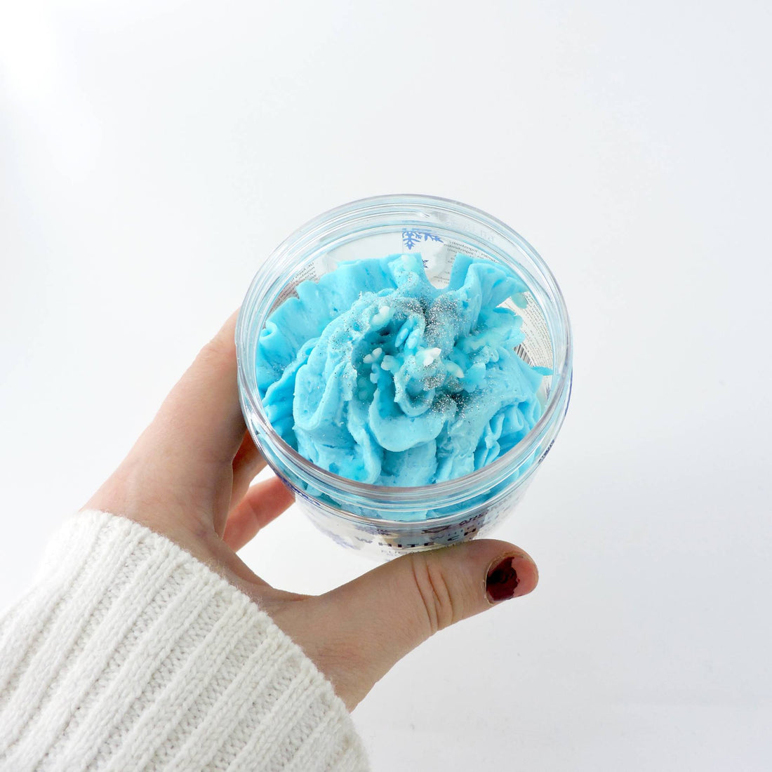 Hand holding a jar of White Christmas Scented Whipped Soap, highlighting its luxurious, soft texture, perfect for enhancing your shower experience with a festive touch.