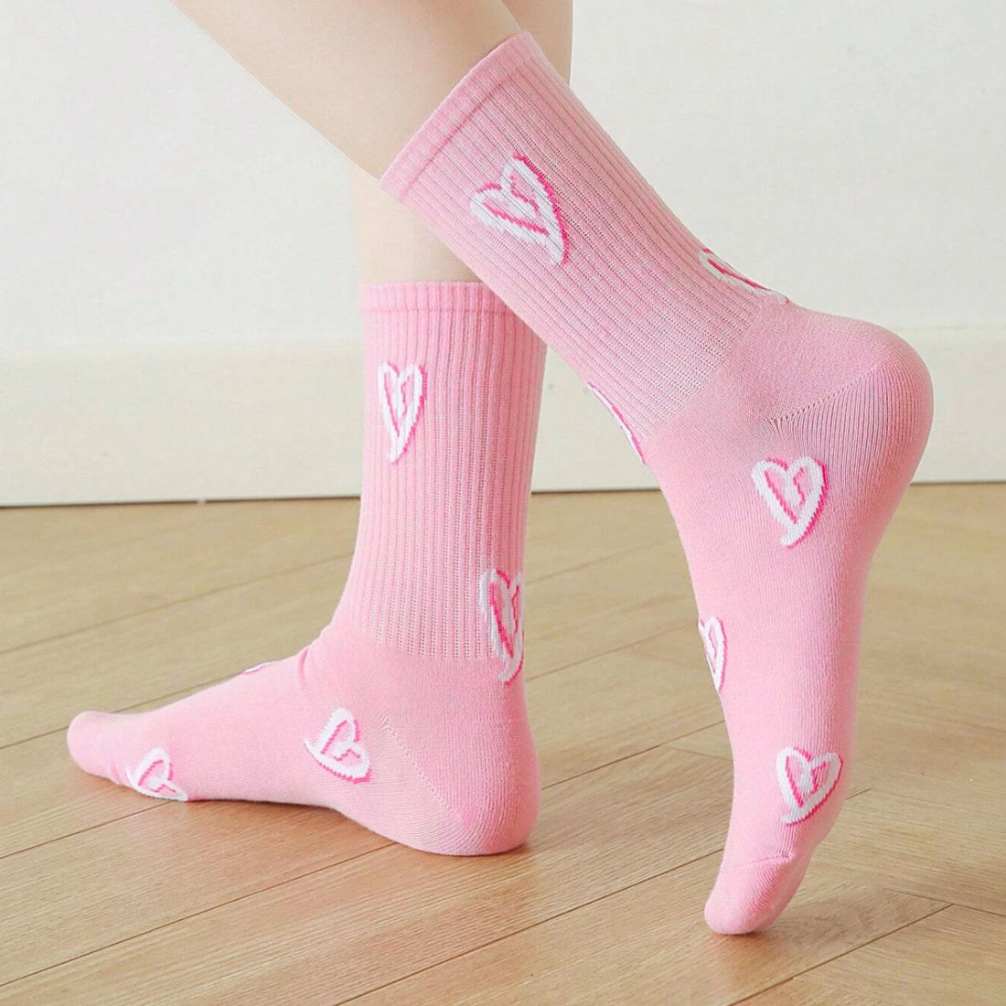 Heart Print Socks - Pink: Feet wearing socks with embroidered white hearts on soft pink fabric, blending playful style with cosy functionality. Ideal for gift boxes.